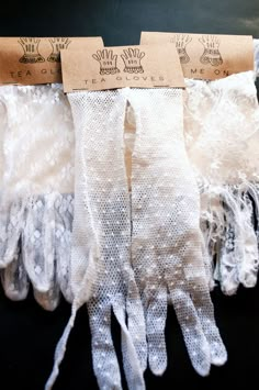 three pairs of white gloves with lace on them sitting next to each other in front of a black background