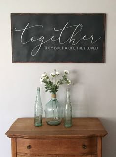 two vases with flowers sit on top of an old dresser next to a sign that says together they built a life they loved