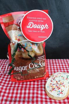 a bag of sugar cookies next to a doughnut on a checkered tablecloth