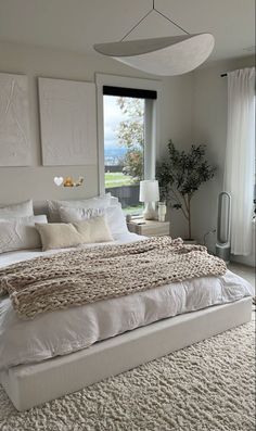 a large white bed sitting in a bedroom next to a window with lots of windows