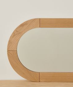 an oval mirror sitting on top of a wooden table