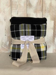 the black and white plaid blanket has a ribbon around it's edge, with a tag on it