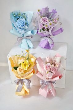 three bouquets of flowers are sitting on a white box