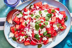 a plate filled with watermelon, onions and feta cheese next to a drink