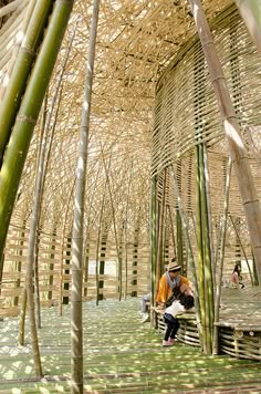 a man sitting on a bench in a bamboo structure