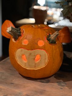 a pumpkin with a cow's face painted on it sitting on a wooden table