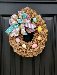 a burlock wreath decorated with easter eggs and a bow on the front door