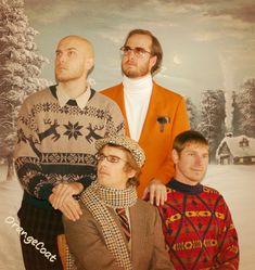 three men standing next to each other in front of a christmas tree and snow covered background