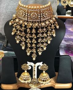 an elaborate necklace and earring set on display in a store window, surrounded by other jewelry items