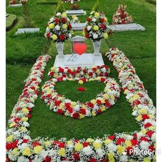 a grave surrounded by flowers and wreaths with a heart on it in the middle