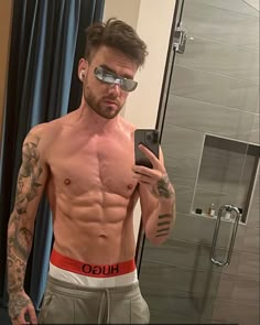 a shirtless man taking a selfie in front of a mirror with his cell phone