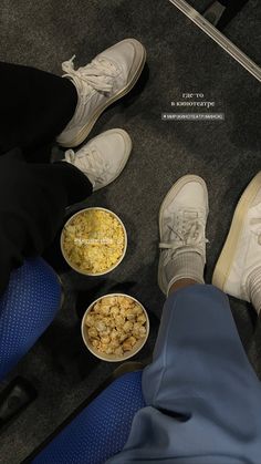 three people sitting on the floor with their feet up and bowls of food in front of them