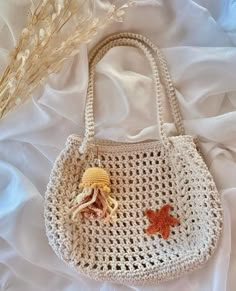 a crocheted bag with an orange starfish on the side and a flower in the middle