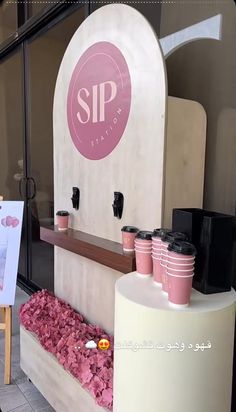 there is a sign that says sip station on the side of this building with pink flowers in front of it