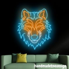 a neon wolf head on a black wall next to a green couch and yellow pillows