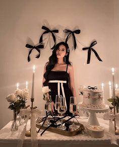 a woman standing in front of a table with cake and wine glasses