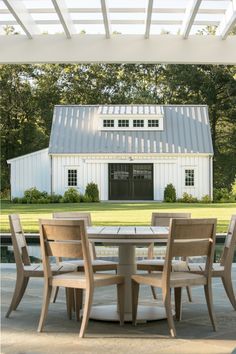 an outdoor table and chairs with a barn in the background