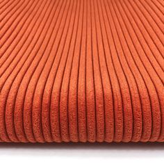 an orange blanket is folded on top of a white surface with lines in the middle