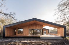 a small wooden house sitting on top of a dirt field next to some bare trees