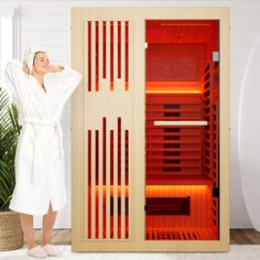 a woman in a bathrobe standing next to an infrared saunator with the door open