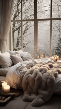 a large bed sitting in front of a window next to a candle and some pillows