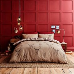 a bed in a room with red walls and wooden flooring that has deer head on it