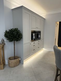 a kitchen with white cabinets and a potted tree in the center, next to a dining room table