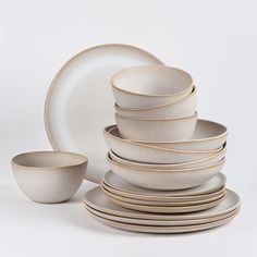 a stack of white plates and bowls on a table