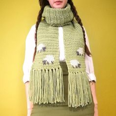 a woman wearing a green scarf with sheep on it and fringes around her neck