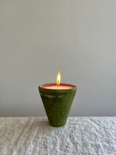 a green candle sitting on top of a white table