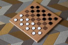 a wooden board game sitting on top of a carpet covered in white and brown squares