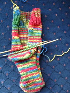 a pair of colorful knitted socks sitting on top of a blue blanket