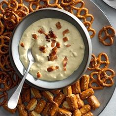 a bowl of dip surrounded by pretzels on a plate