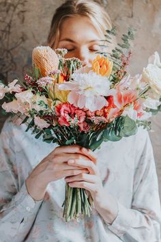 a woman holding a bouquet of flowers in front of her face