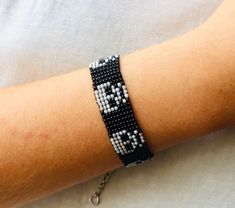 a person wearing a black and white beaded bracelet with silver beads on their arm