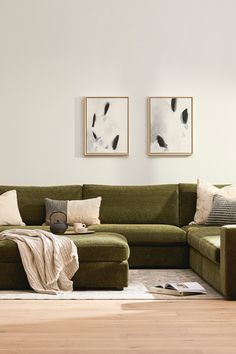 a living room with a green couch and two pictures on the wall above it,