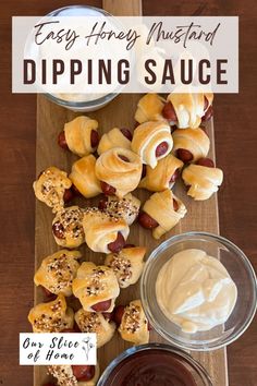 pigs in a blanket with dipping sauce next to it on a wooden cutting board,