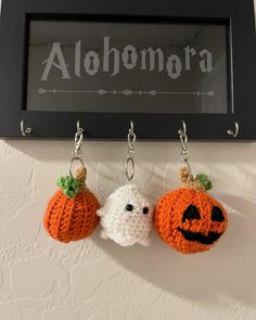 two crocheted pumpkins hanging from hooks on a wall with the word alohama written above them