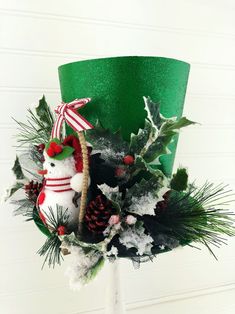 a christmas wreath with a snowman and pine cones on it, sitting in front of a green lamp shade