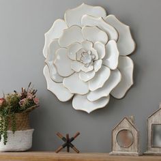 a large white flower is mounted on the wall above a mantel with two small bird houses