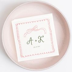 a white plate with a pink and green monogrammed napkin on top of it