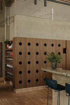 an empty bar with three blue chairs and a vase full of flowers on the counter