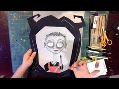 someone is making a paper cut out of a man's face with scissors and other crafting supplies