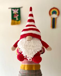 a knitted santa clause hat on top of a small toy gnome figurine