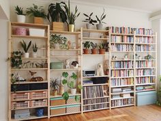 a room filled with lots of books and plants