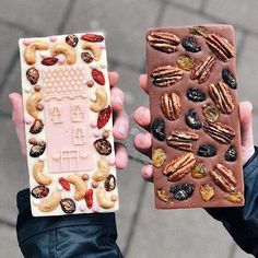 two people holding up different types of food and one is holding a piece of chocolate