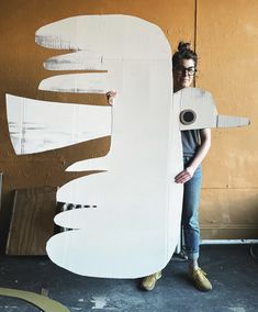 a woman standing next to a large cardboard cut out of a bird's wing