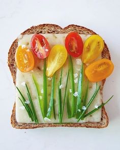 slices of bread with tomatoes, onions and chives on them sitting on a white surface