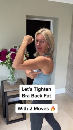 a woman is flexing her muscles in the living room with flowers on the table