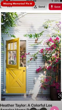 a yellow door and some pink flowers on the side of a house